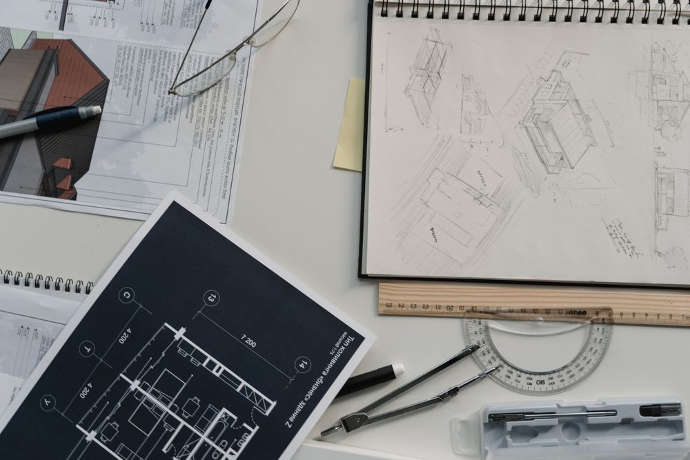 Architectural sketches, floor plans, and drafting tools on a studio desk